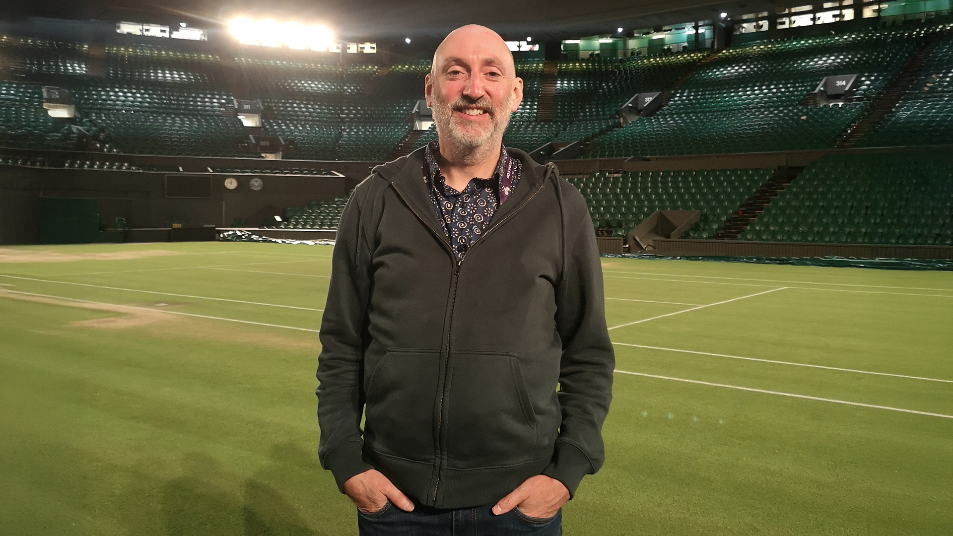 Man stood smiling in a sports outdoor stadium