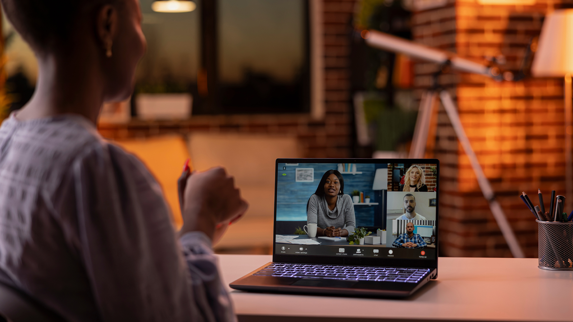 Black woman focused on productive online conversation with diverse professionals, attending virtual business call on laptop.