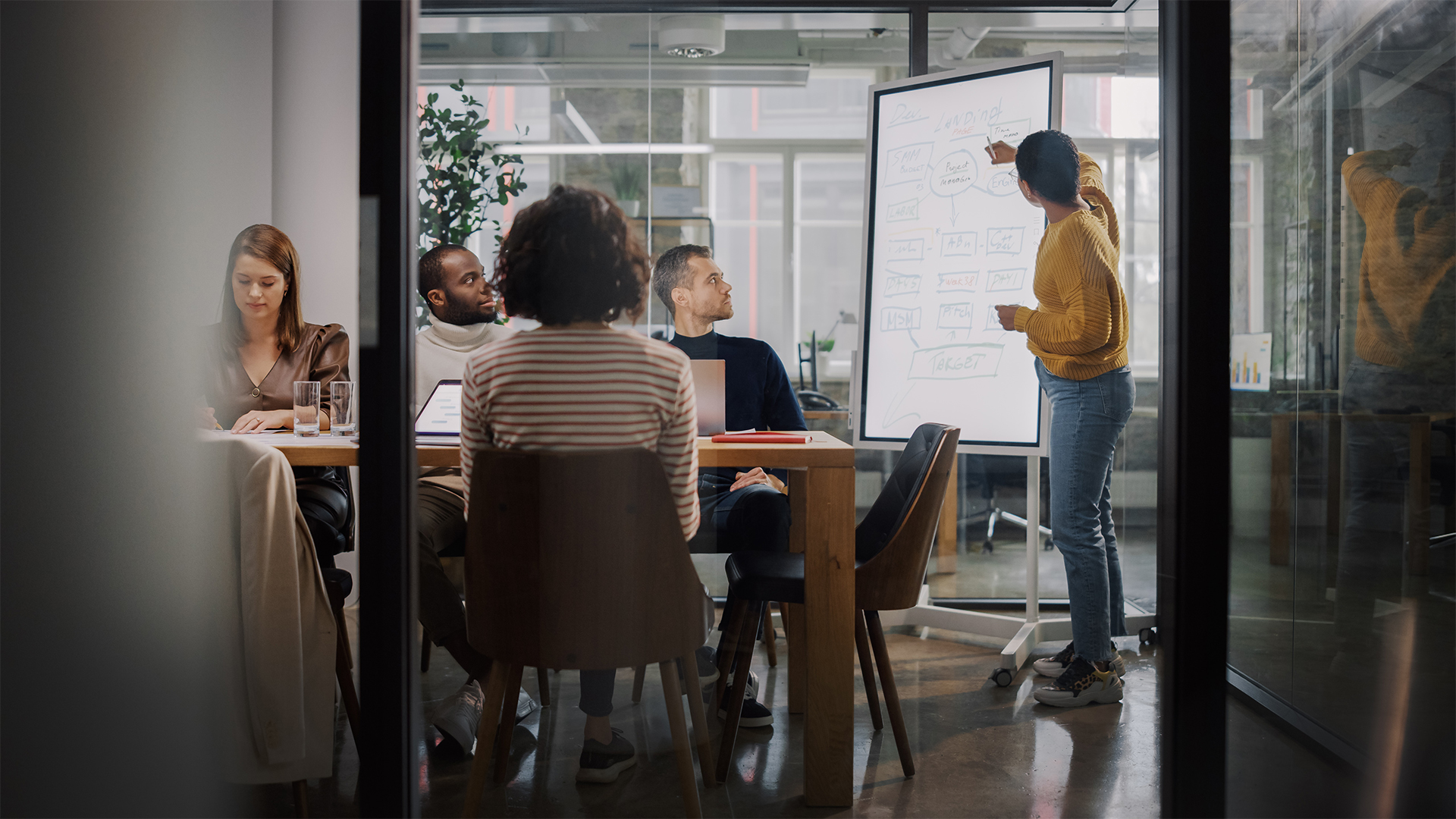 Project Manager Makes a Presentation for a Young Diverse Creative Team in Meeting Room in an Agency